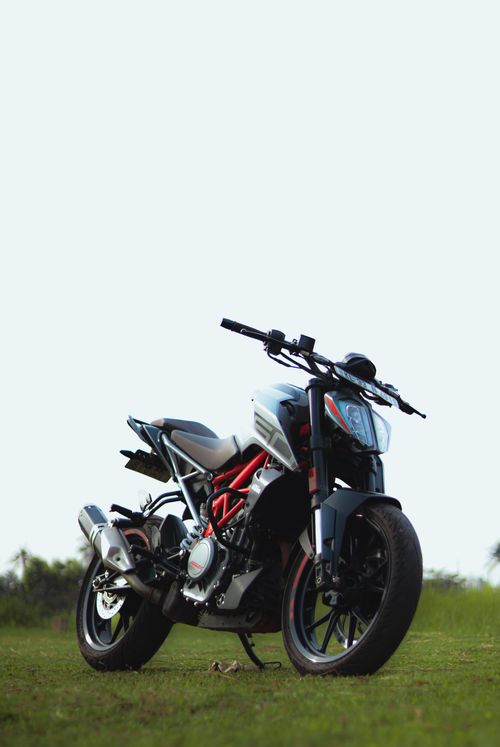 Free A modern motorcycle parked on a lush green field under a clear sky in India. Stock Photo