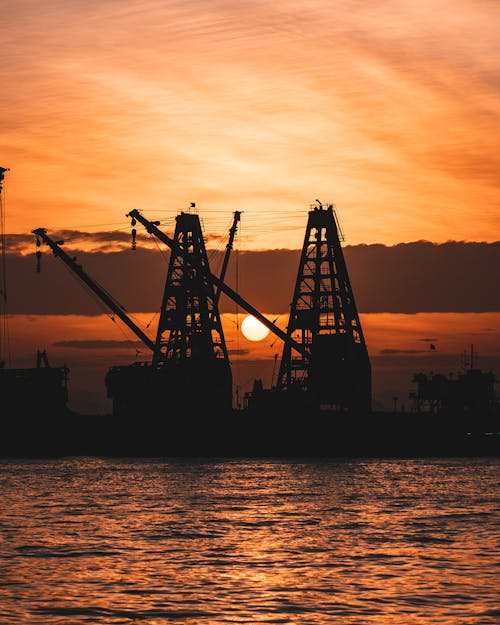 Silhouetted Cranes in a Dock at Sunset