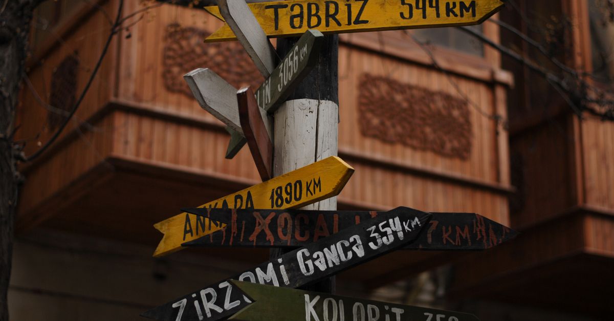 A wooden signpost with multiple direction arrows at a crossroads, representing choosing the right SpyFu alternative