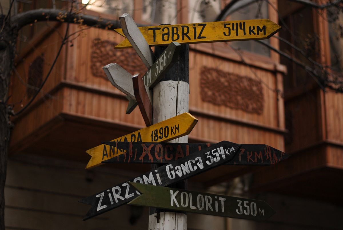 A multi-directional wooden signpost on a city street with timber buildings behind