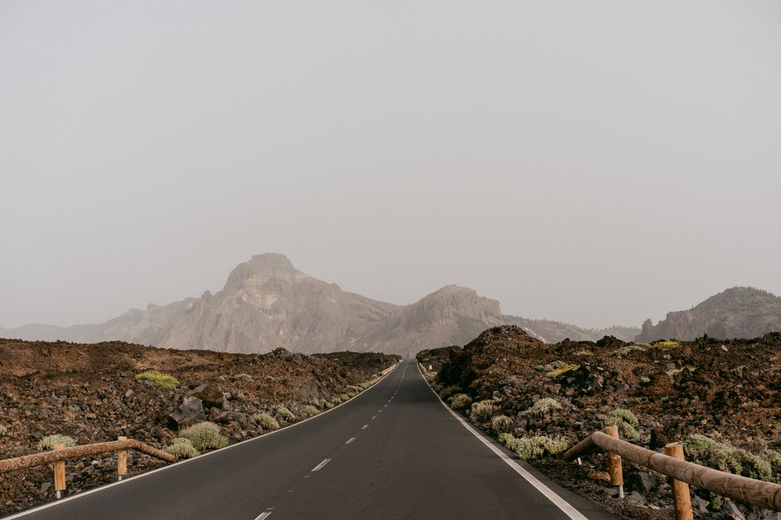 Road running through a rocky desert landscape toward distant mountains