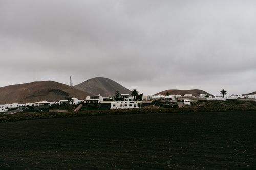 Free A peaceful town nestled among hills under an overcast sky, showcasing a serene landscape. Stock Photo