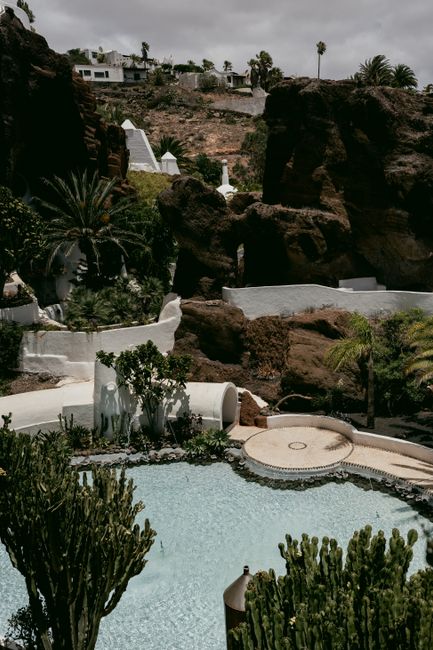 A luxurious resort on a mountainside featuring a stunning swimming pool amidst lush greenery and rock formations.