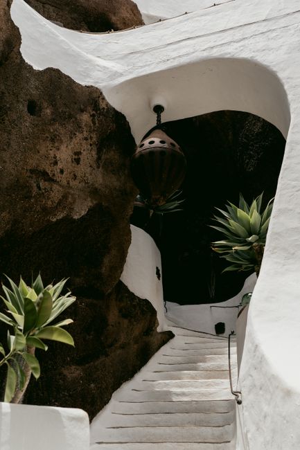 A picturesque stone staircase in a cave passageway surrounded by white walls and greenery.