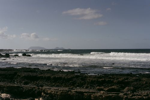 Free Dramatic view of a rocky shoreline with crashing waves under a clear sky. Stock Photo