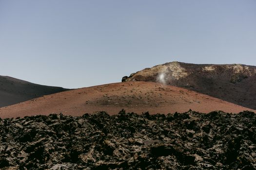 A breathtaking view of a barren volcanic landscape with rugged rocky terrain under clear skies.