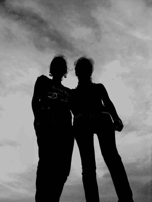 Free Artistic silhouette of two women standing under a cloudy sky, showcasing friendship. Stock Photo
