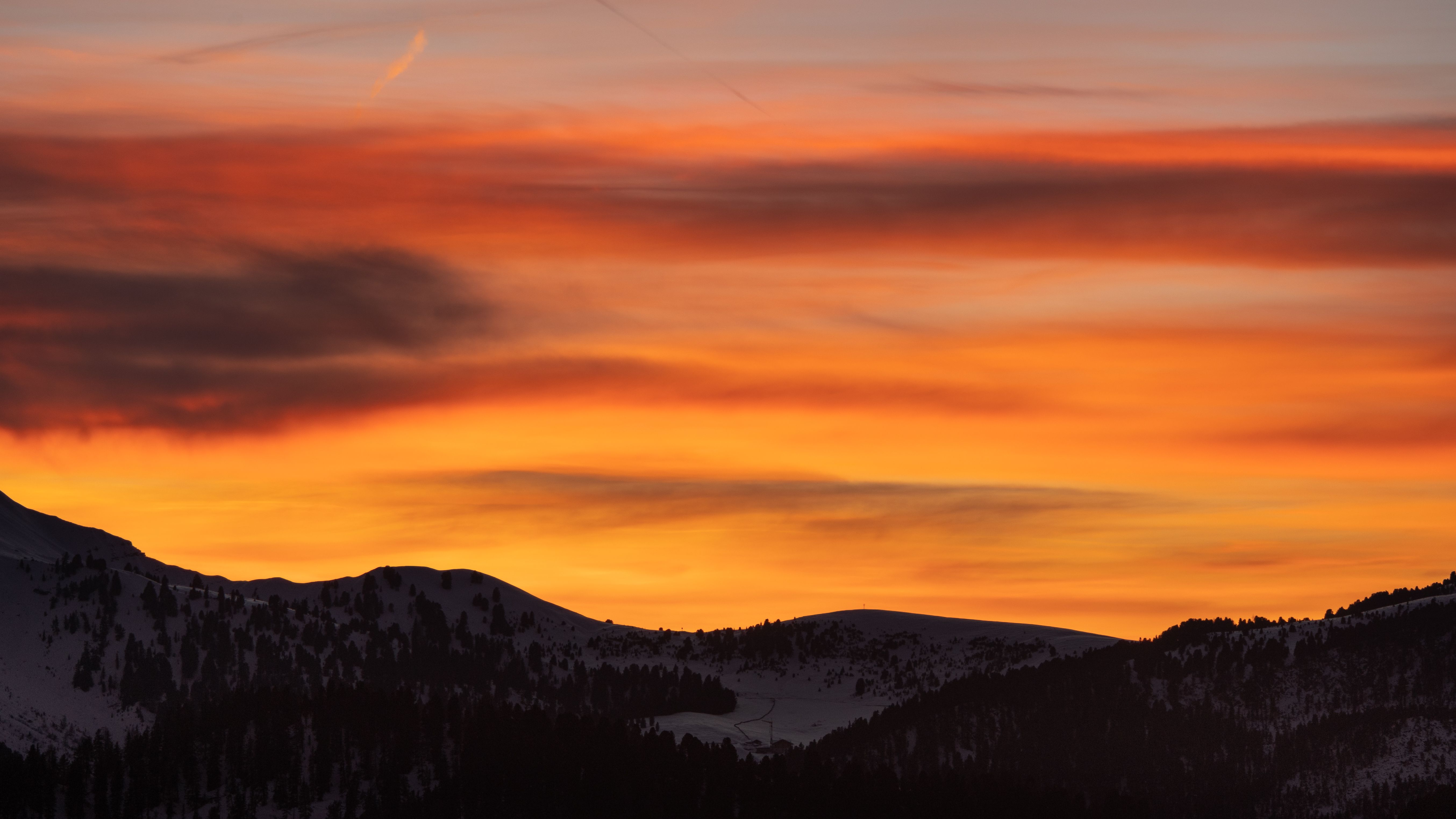 A sunset over a mountain range with snow covered trees · Free Stock Photo