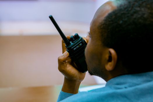 African man talking on a handheld radio device in Kigali, Rwanda.