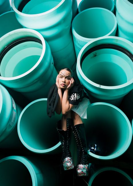 Artistic portrait of a woman in edgy boots posing with turquoise pipes in Orlando.