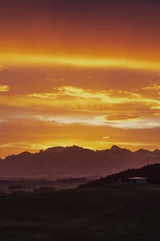 A breathtaking sunset over a silhouetted mountain range with vibrant clouds.