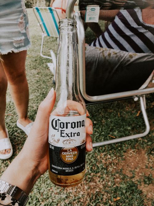 Free Close-up of a hand holding a Corona beer bottle in an outdoor setting, perfect for lifestyle imagery. Stock Photo
