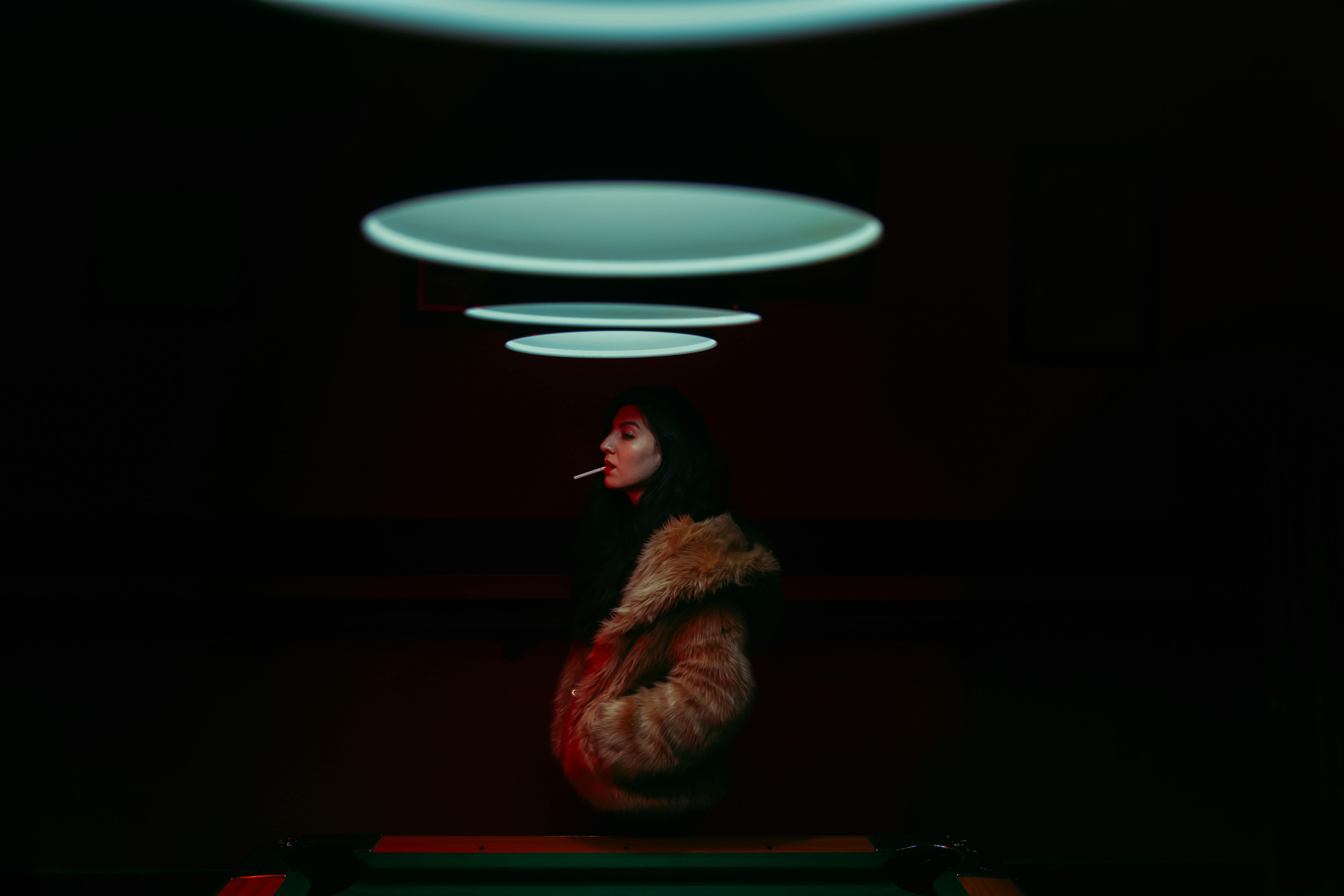 woman with a cigarette in her mouth standing by the billiard table