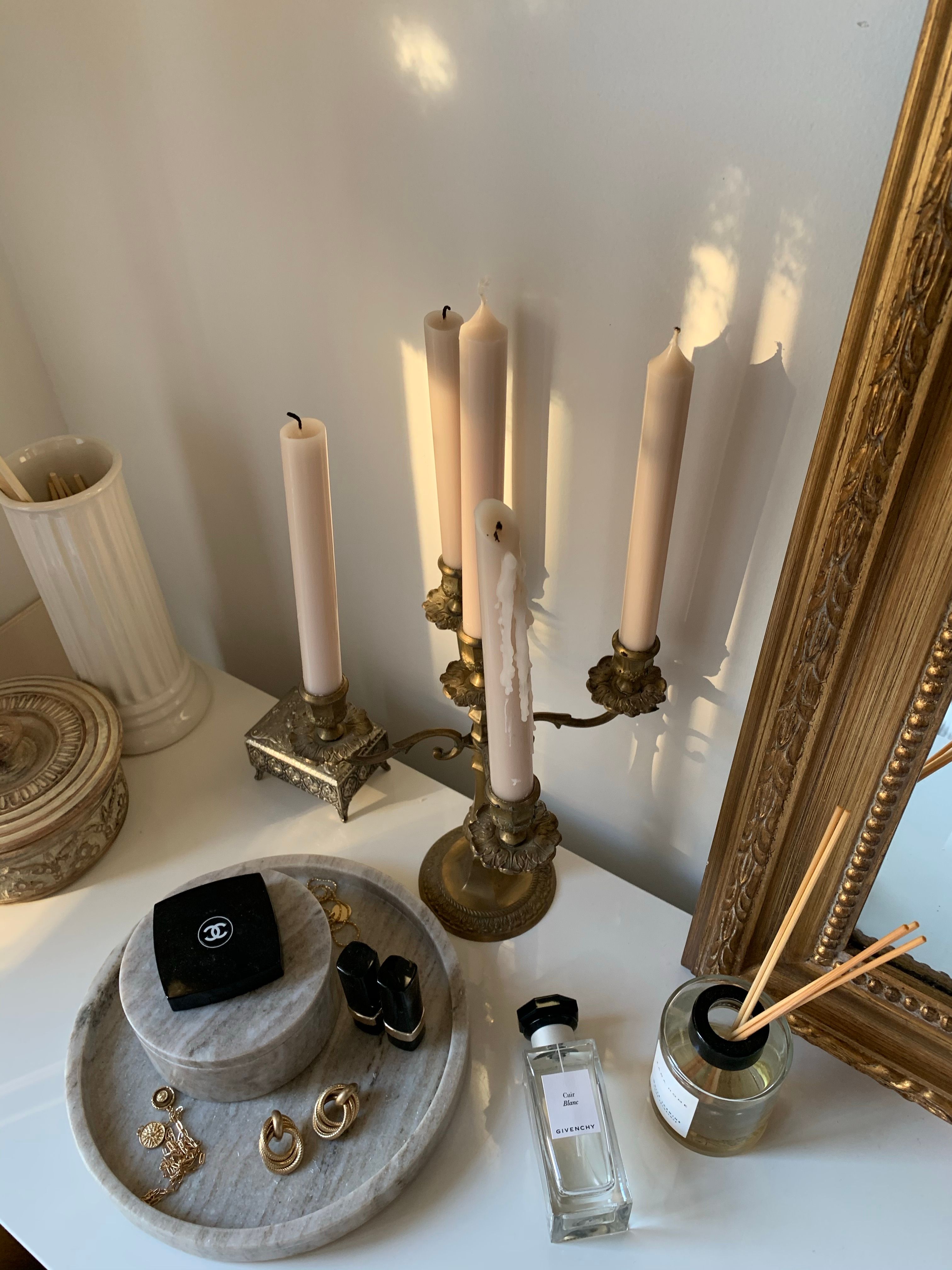 A sophisticated still life featuring candles, jewelry, and stylish decor elements.