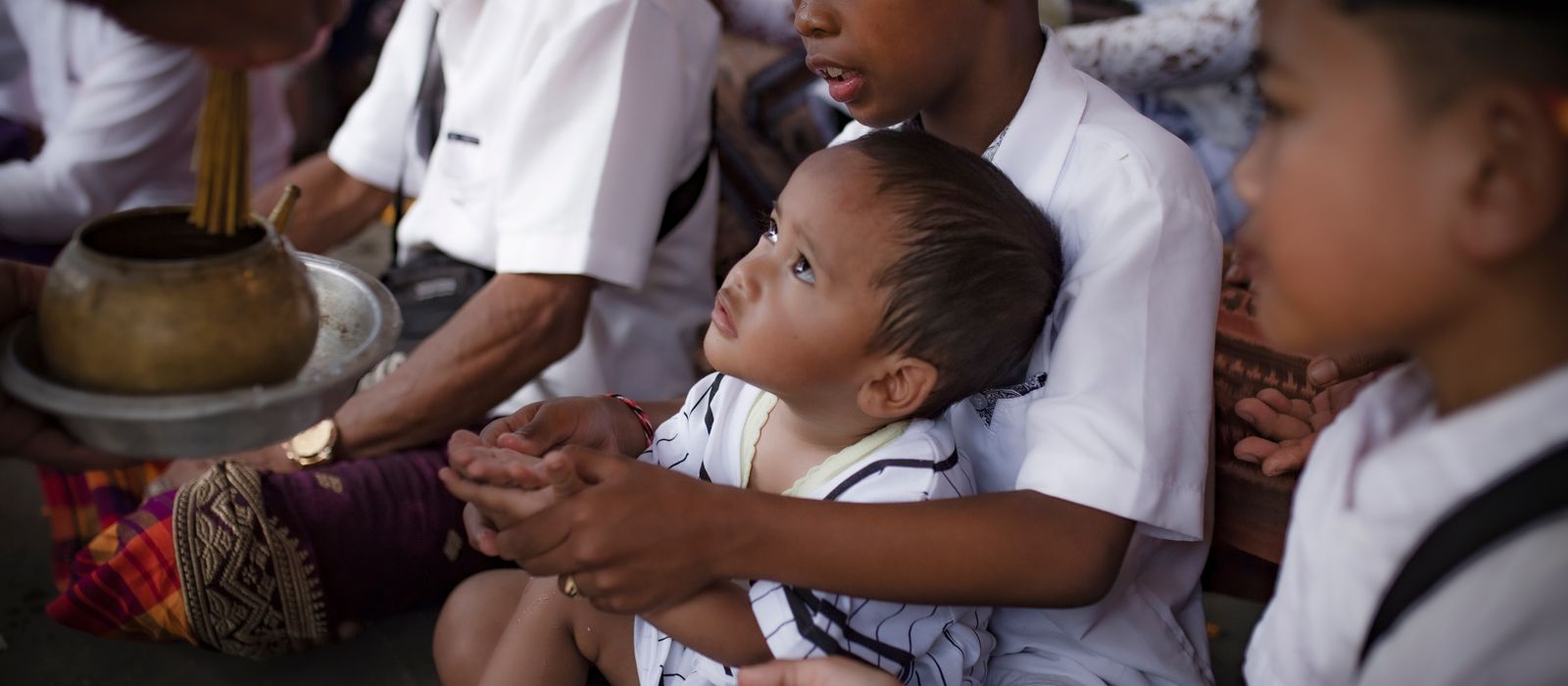 Children in traditional attire at a temple ceremony in Denpasar, Bali.