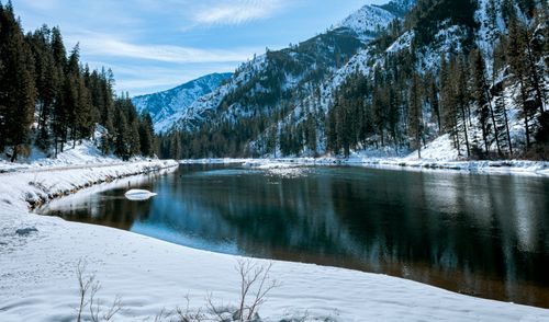 Free Breathtaking winter view of a snowy river surrounded by mountains and forests. Stock Photo