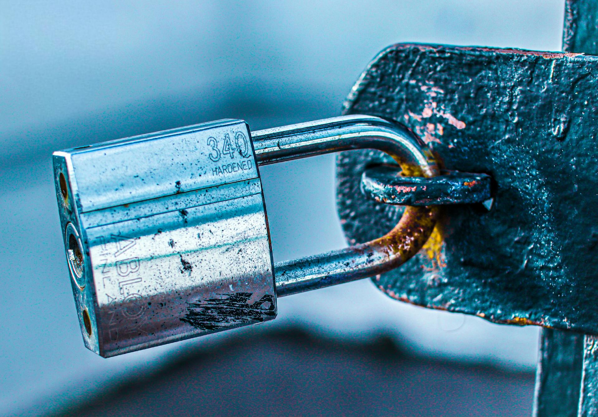 Detailed close-up of a durable padlock securing a rusted metal gate, emphasizing safety and protection.