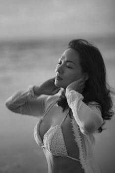 Elegant black and white portrait of a woman in a bikini at the beach.