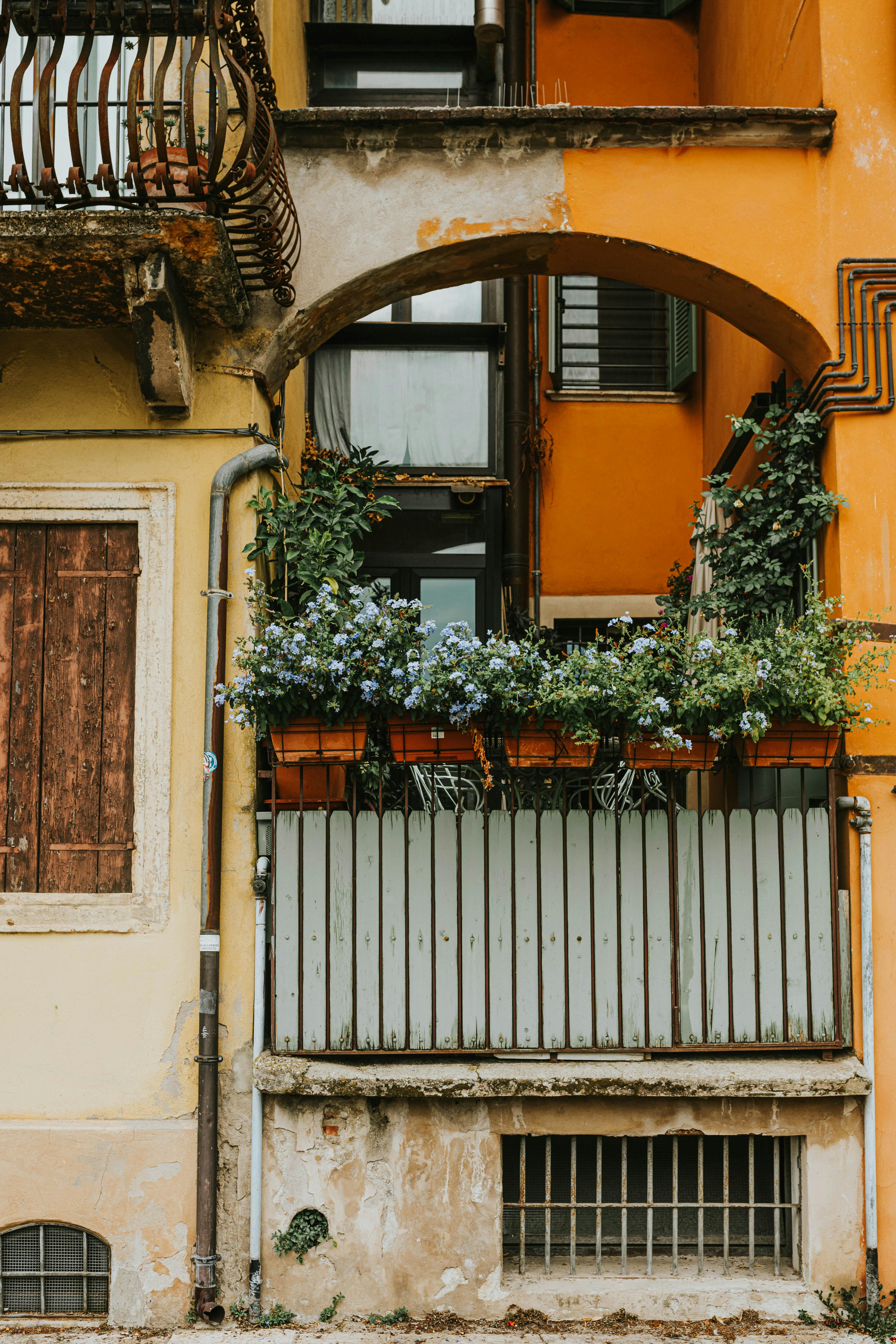 Rustic Italian balcony adorned with vibrant flowers and foliage.