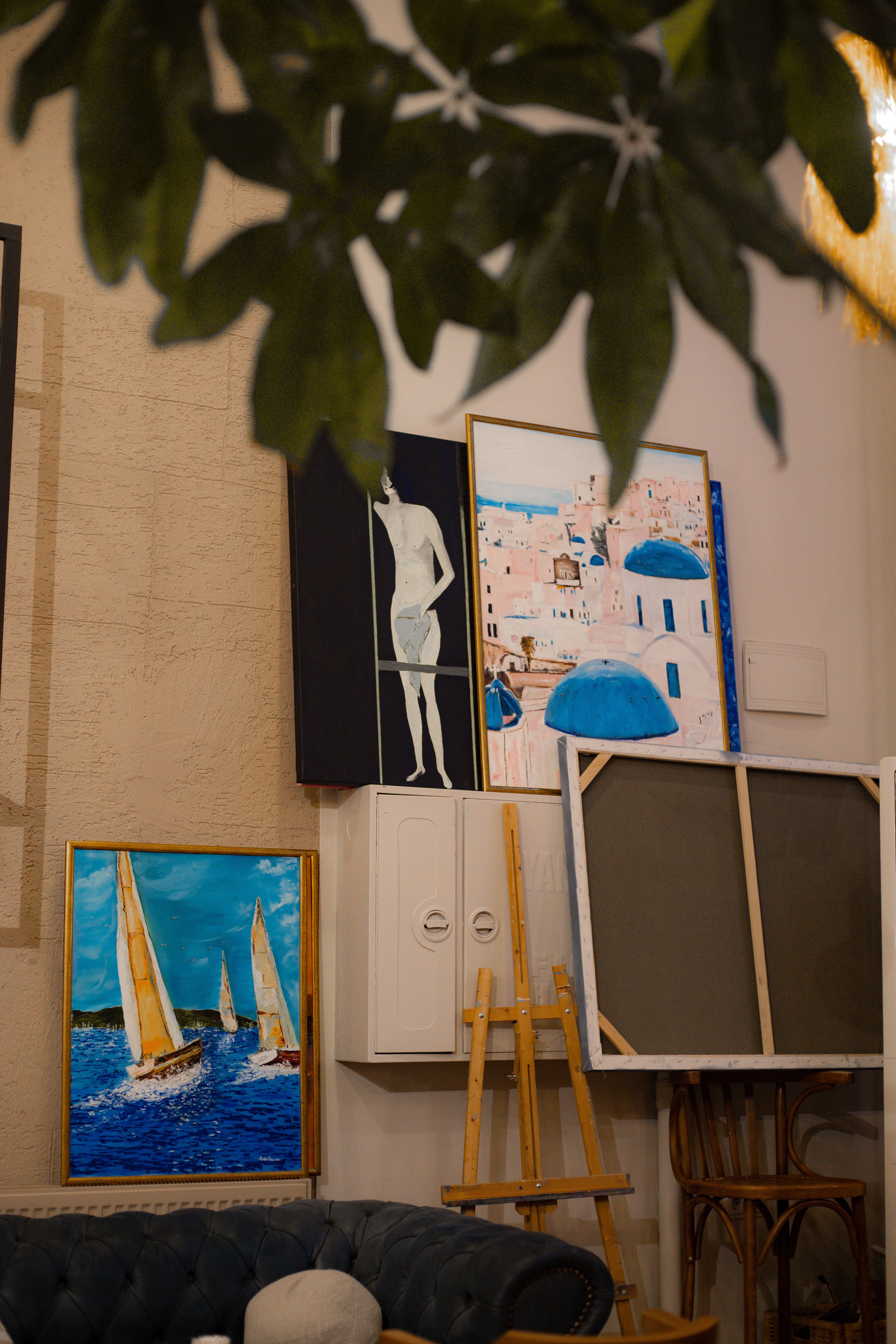 A cozy art studio featuring nautical and abstract paintings on easels and walls.