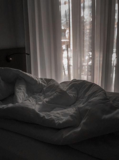 Free A cozy unmade bed with white sheets near a sunlit window in Sosnivka, Ukraine. Stock Photo