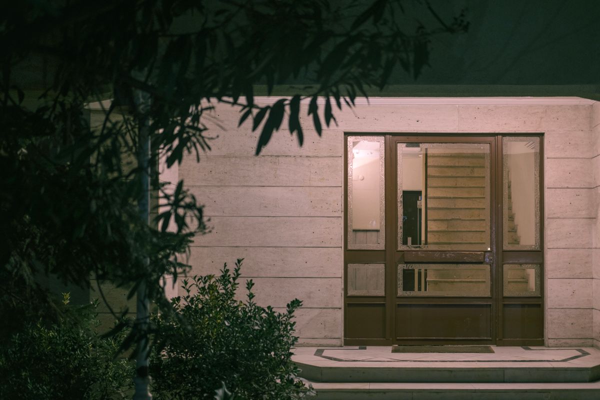 A lit stone entrance screened by planting at night. Photo by Yusuf Celik on Pexels