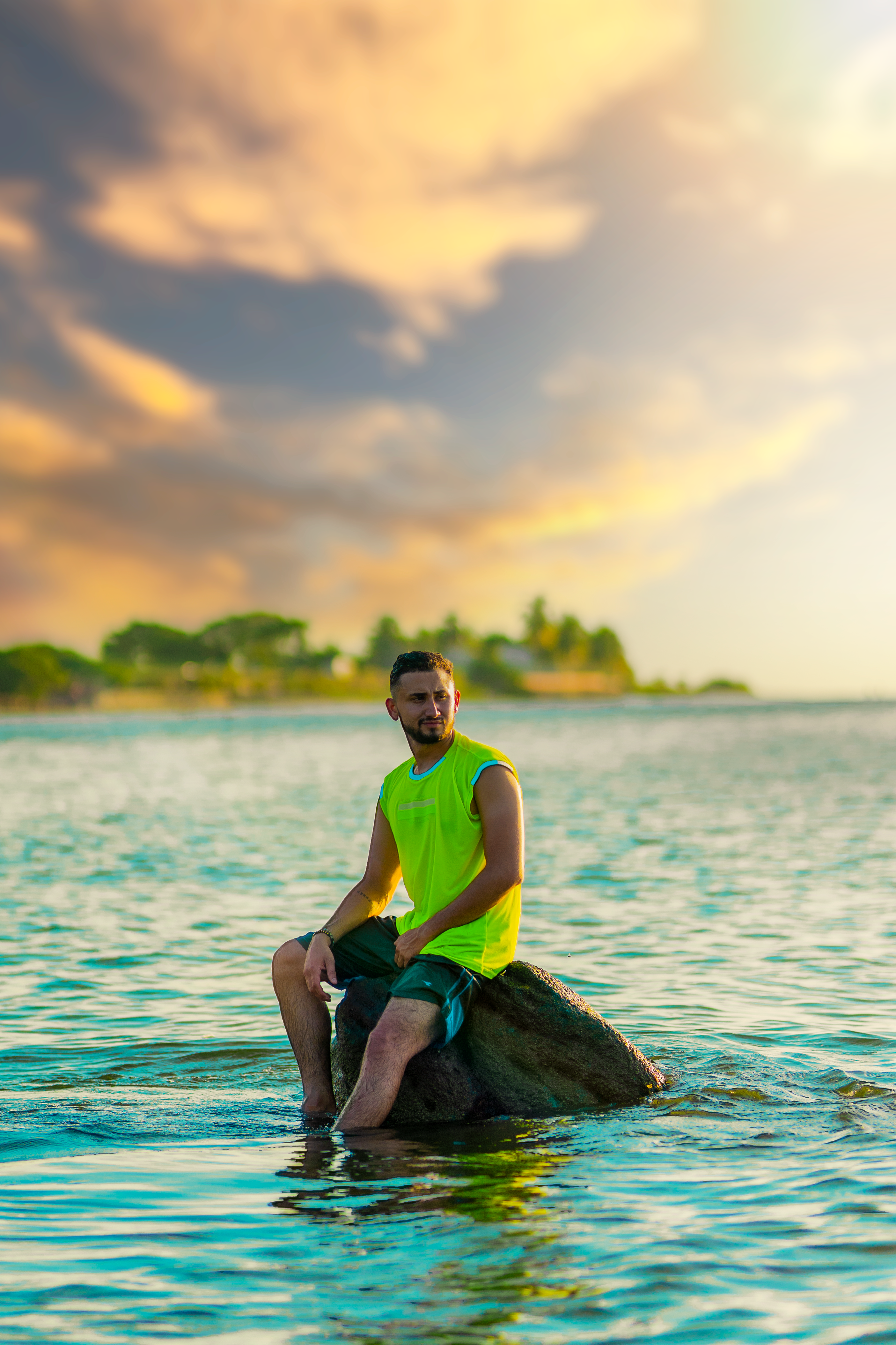 Man Sitting on a Rock in the Water at Sunset · Free Stock Photo