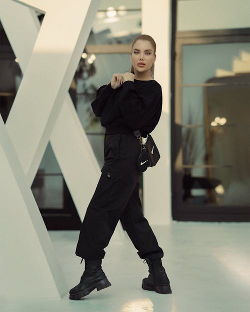 Young Woman in a Trendy, All Black Outfit Posing in a Modern Building 