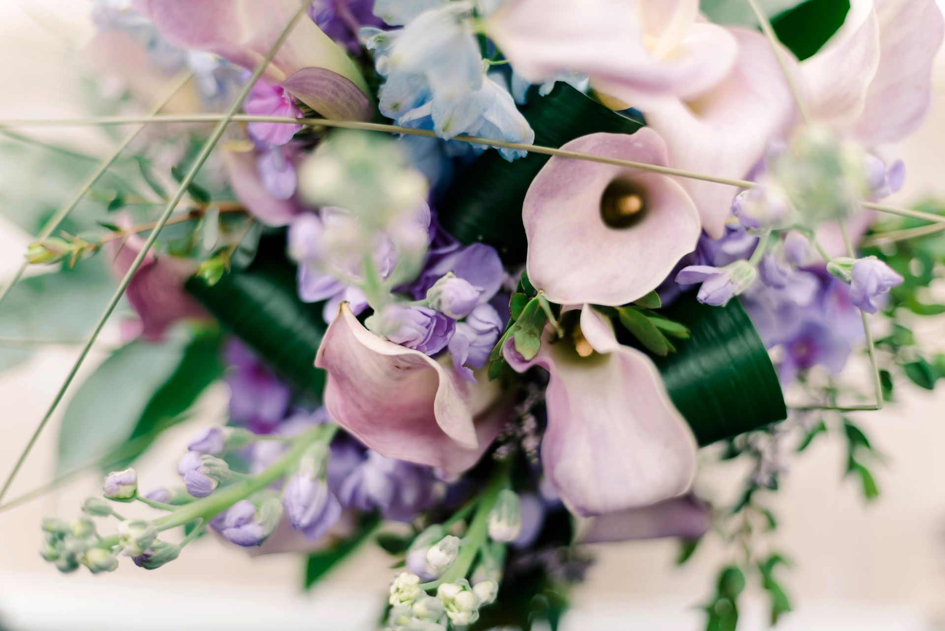 Close-up of a pastel flower bouquet featuring pink calla lilies and violet blooms, perfect for floral design inspiration.