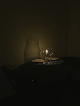 Elegant candlelit dinner setting with wine glasses and plates on a table, creating a cozy ambiance.