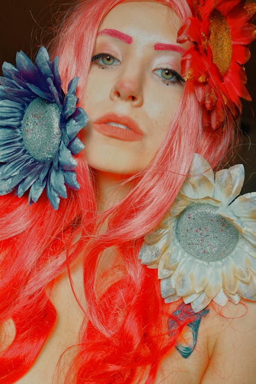 Photo of a Young Woman with Pink Hair Lying with Flowers around Her Head 