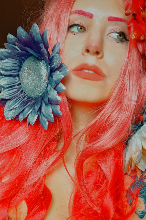Photo of a Young Woman with Pink Hair Lying with Flowers around Her Head