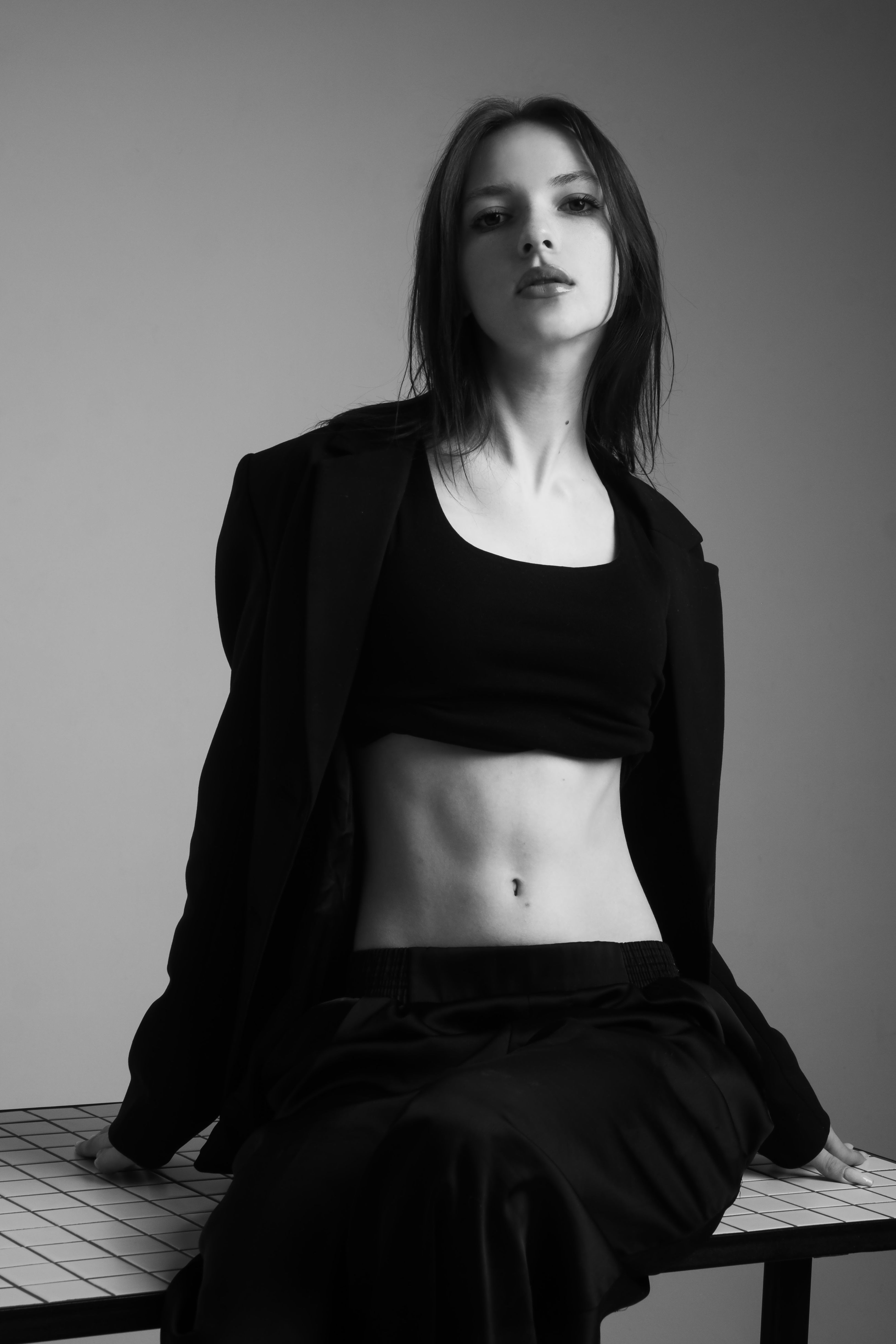 Stylish black and white portrait of a woman posing in fashionable attire, exuding elegance and confidence.