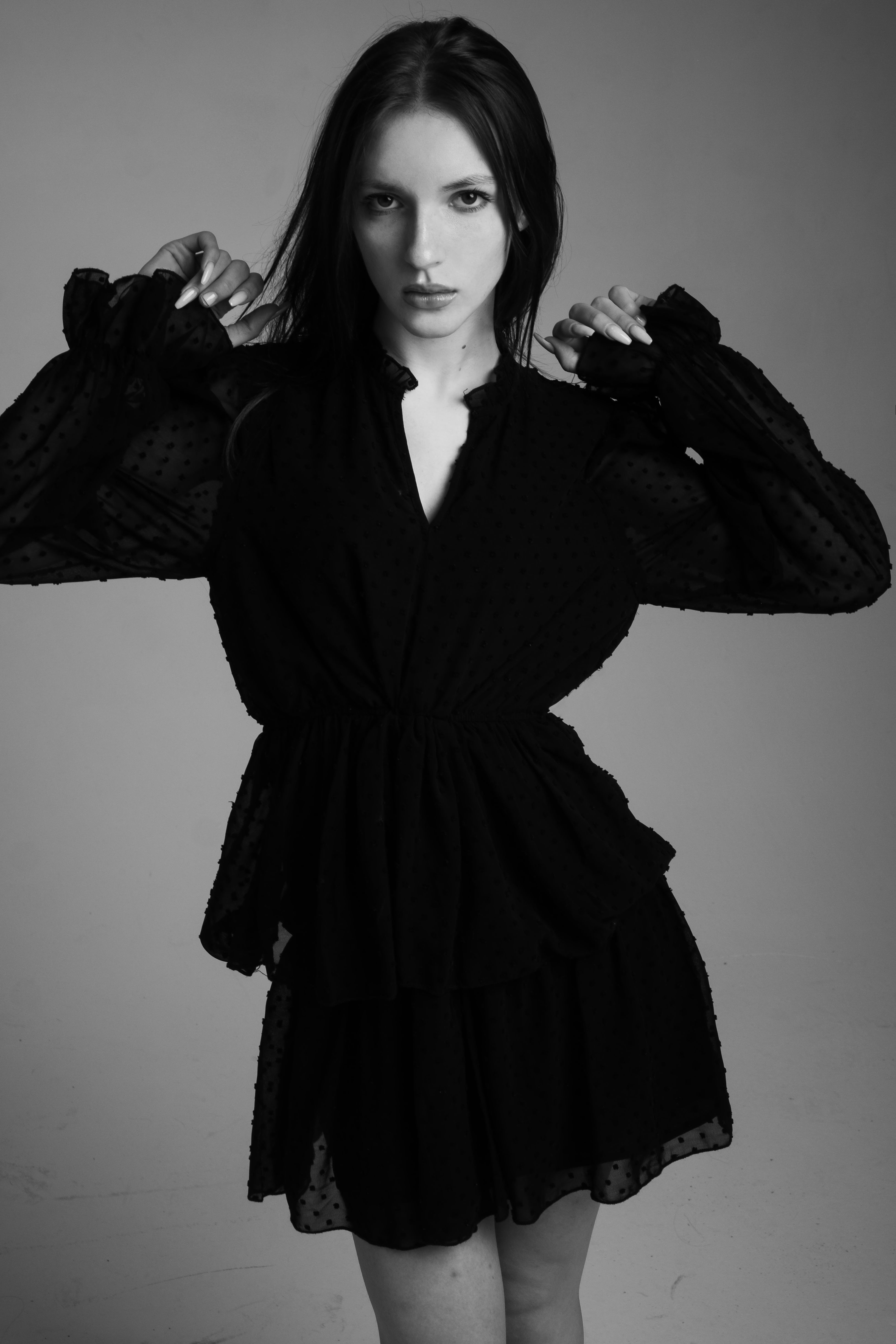 A stylish portrait of a woman posing in a black dress, showcasing fashion elegance.