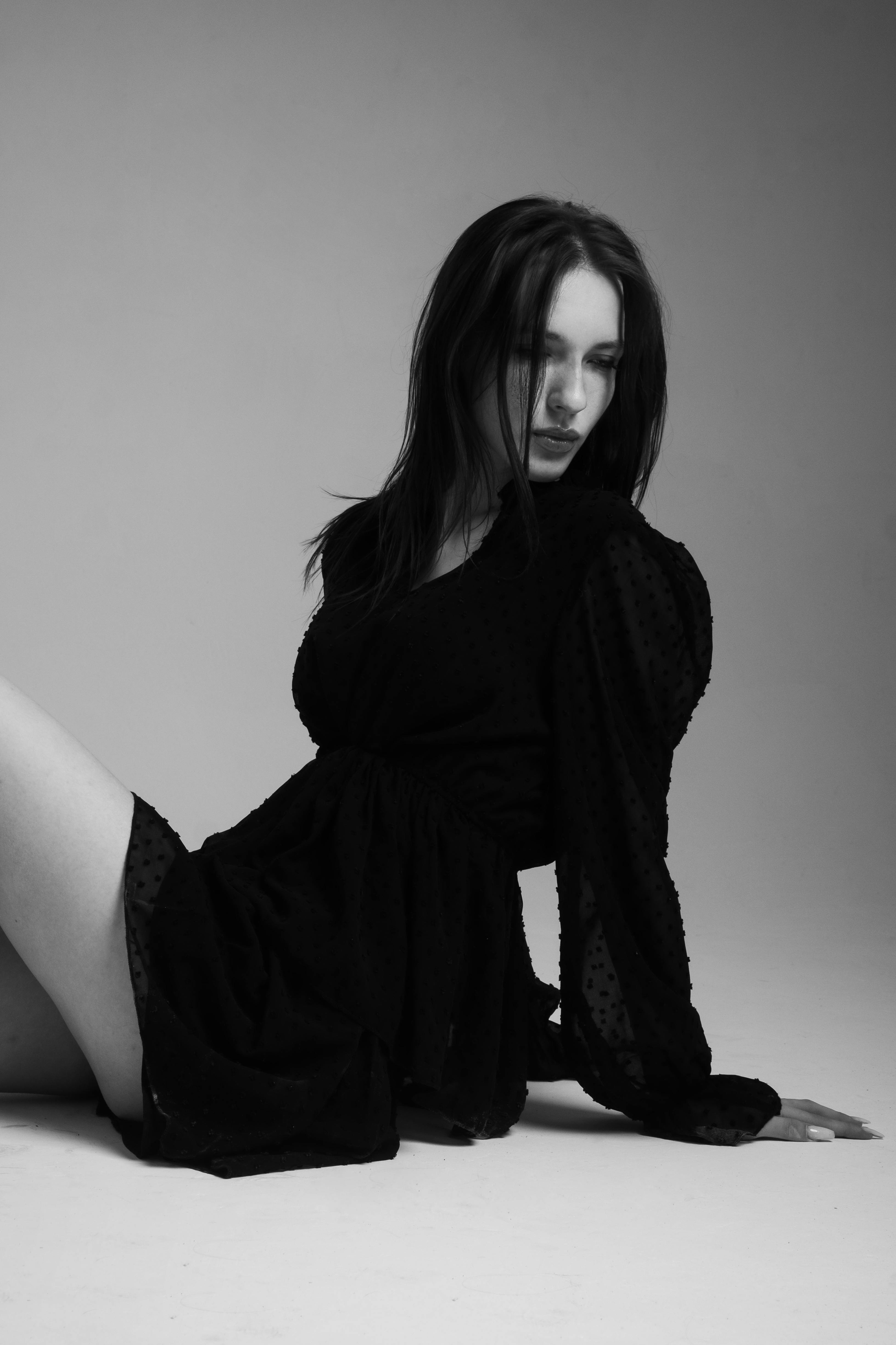 Elegant monochrome photo of a woman posing in a black dress.