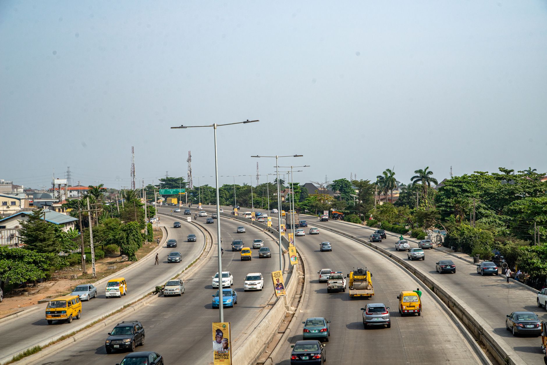 An aerial view of a bustling highway with palm trees, vehicles, and clear skies.