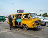 A dynamic street view capturing commuters boarding a classic yellow bus in a lively urban setting.
