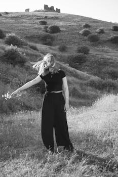 A woman in motion captured in a black and white portrait amidst a tranquil, lush landscape.