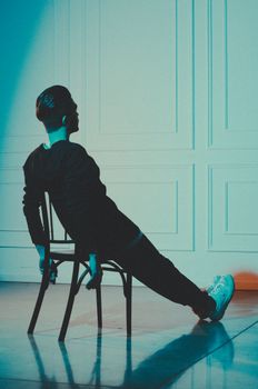 Man in stylish pose on chair, moody lighting, creative photo.