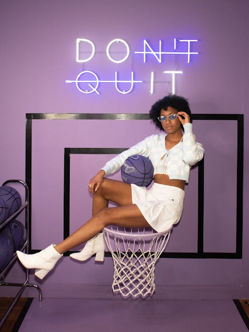 Woman Sitting on Basketball Ring with Ball