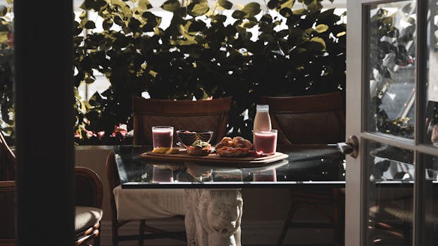 A cozy morning breakfast setup with smoothies and pastries on a sunlit table.