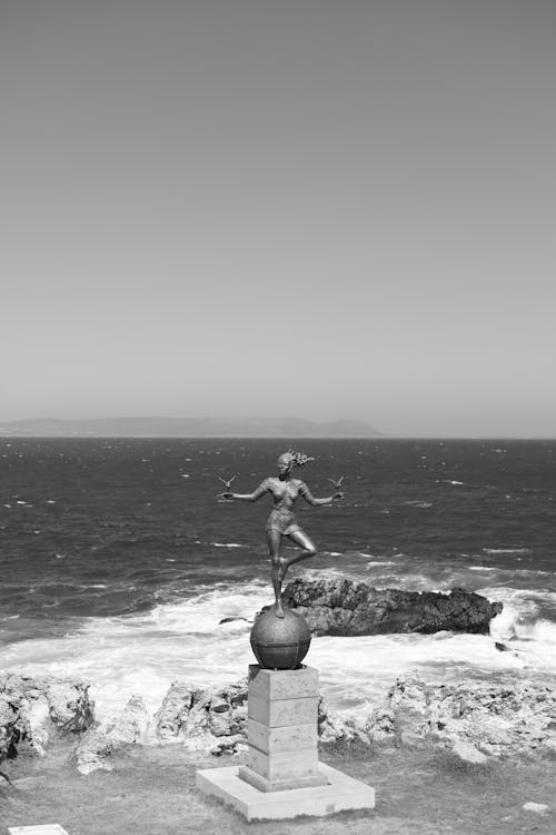 A black and white photo of a statue on the beach