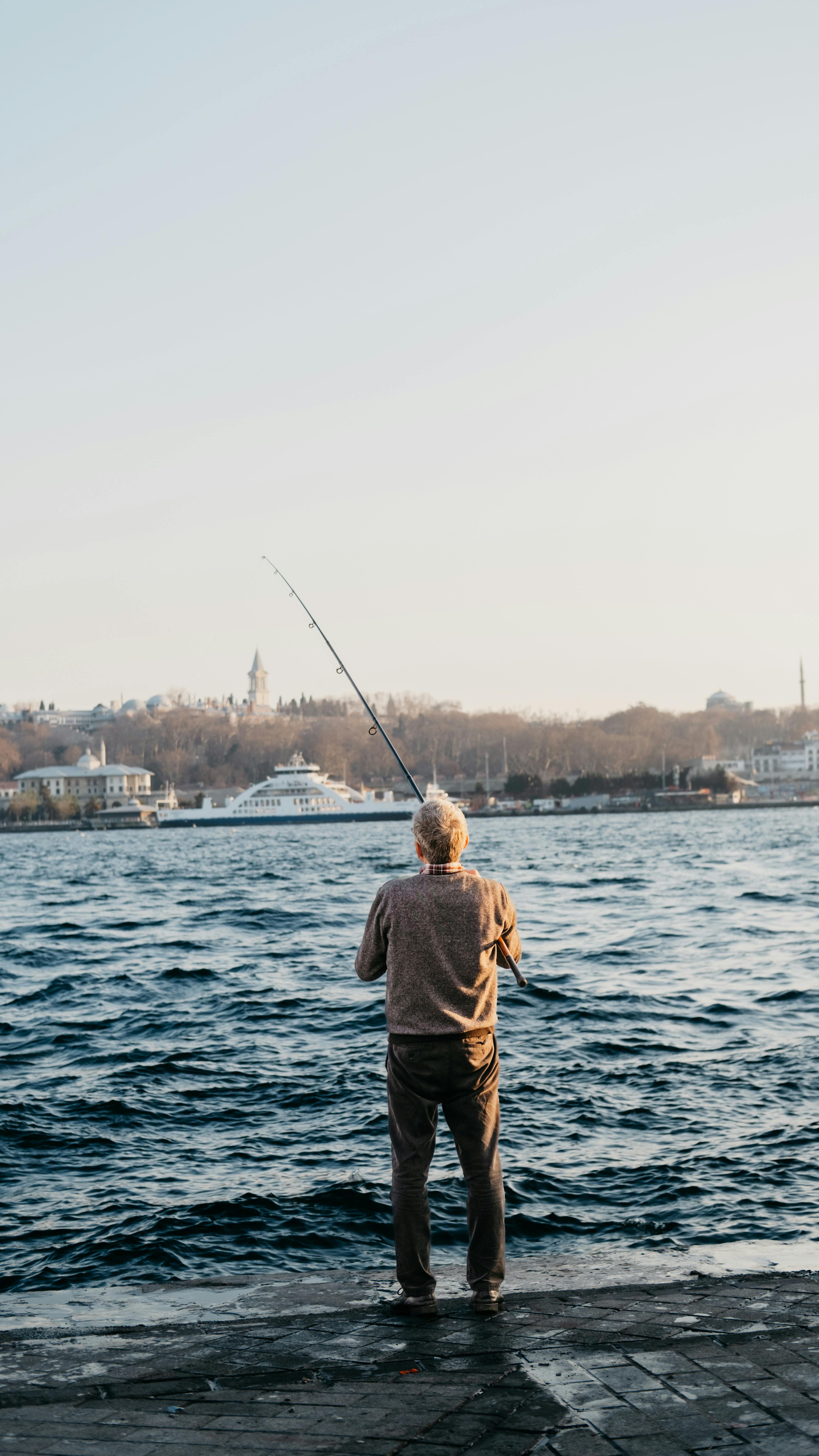 Back View of a Man Fishing on the Sea under the Sky · Free Stock Photo
