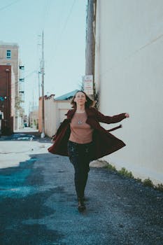 Confident woman in stylish outfit walks through urban alley, embracing the city vibe.