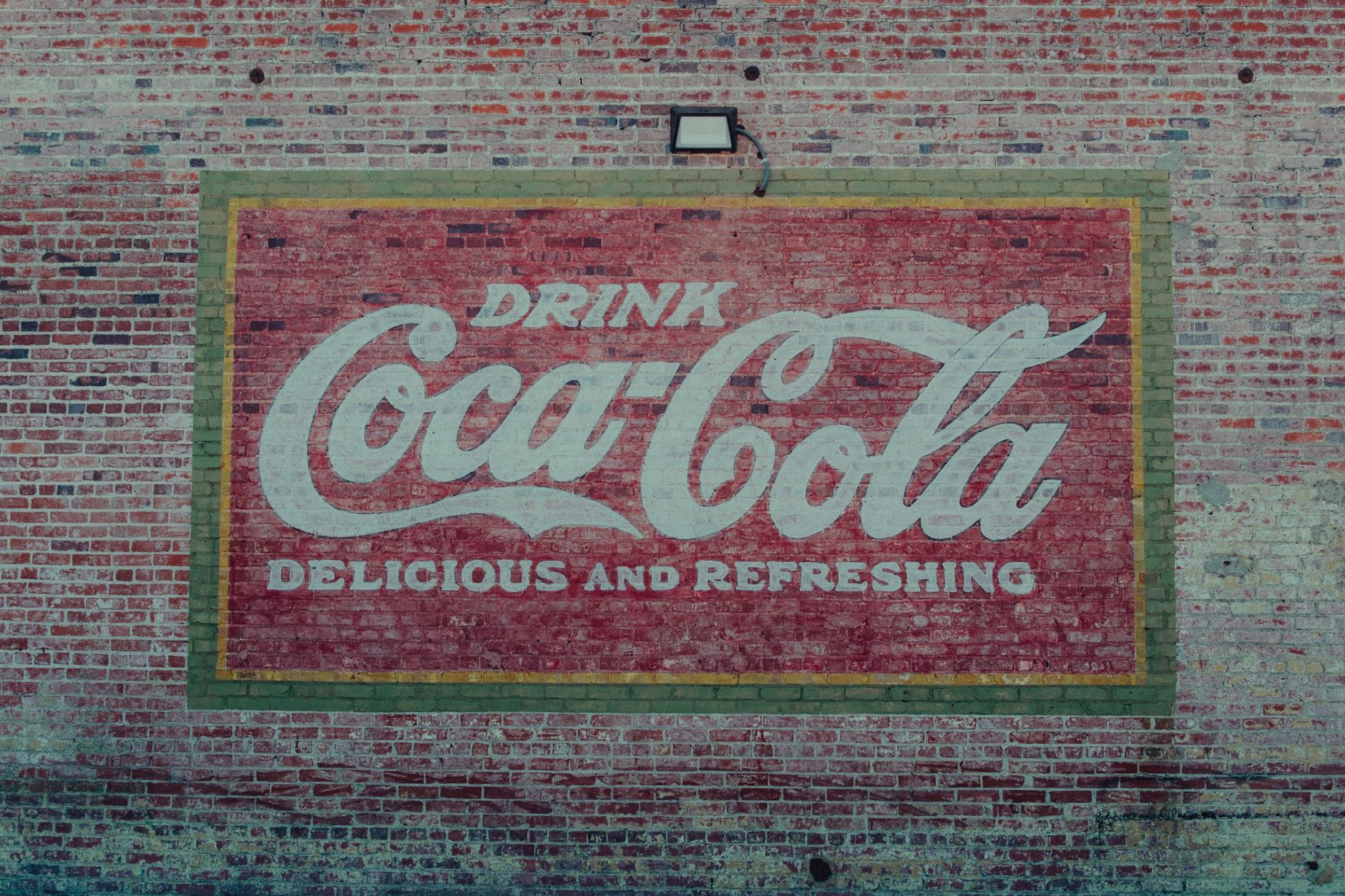 A classic Coca-Cola mural painted on a brick wall, highlighting retro urban art.
