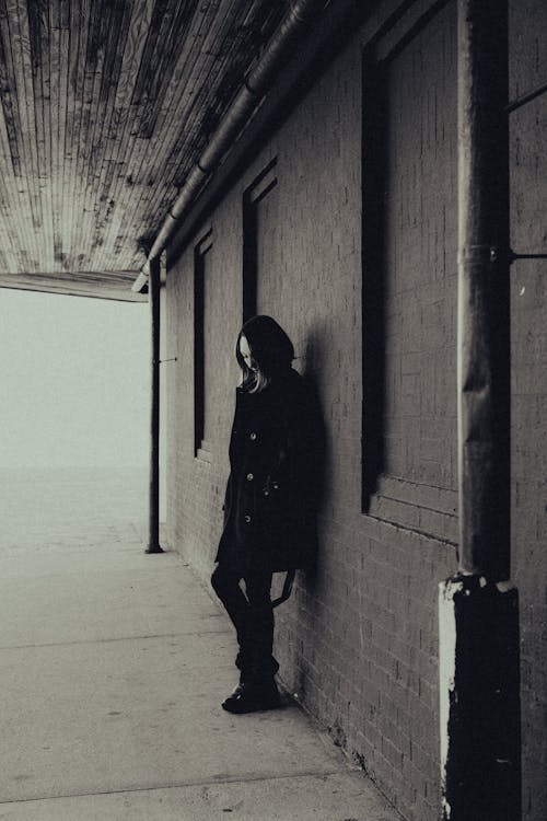 Woman Wearing Coat in Front of Brick Building in Black and White 