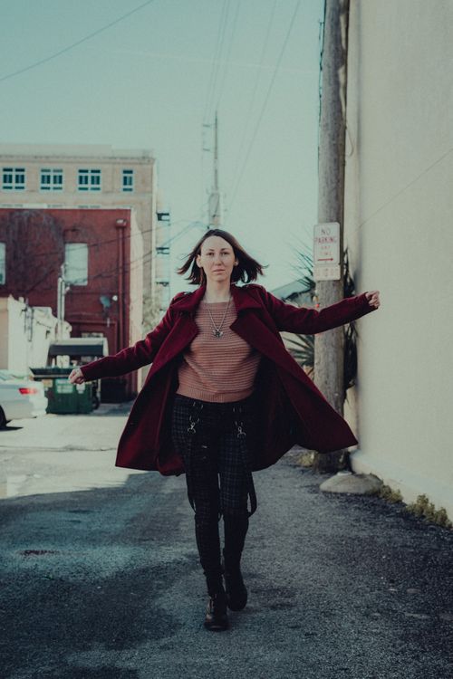 Free Stylish woman in red coat walks confidently down a city street on a sunny fall day. Stock Photo