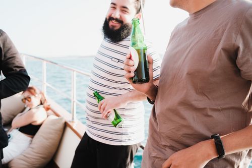 Free Group of friends relaxing and drinking beer on a yacht under the summer sun. Stock Photo