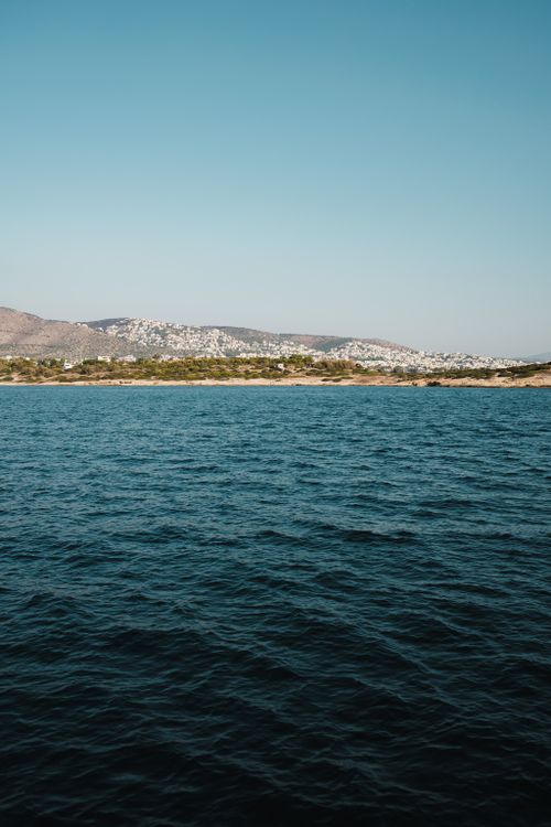 Free A stunning view of a coastal town with hills in the background under a clear blue sky. Stock Photo