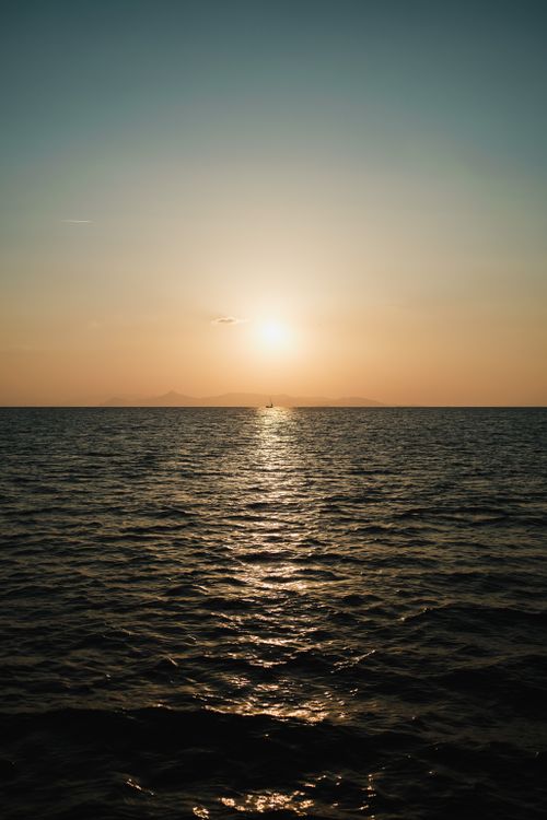 Free Peaceful ocean sunset with golden hues reflecting on the water, creating a calming seascape. Stock Photo